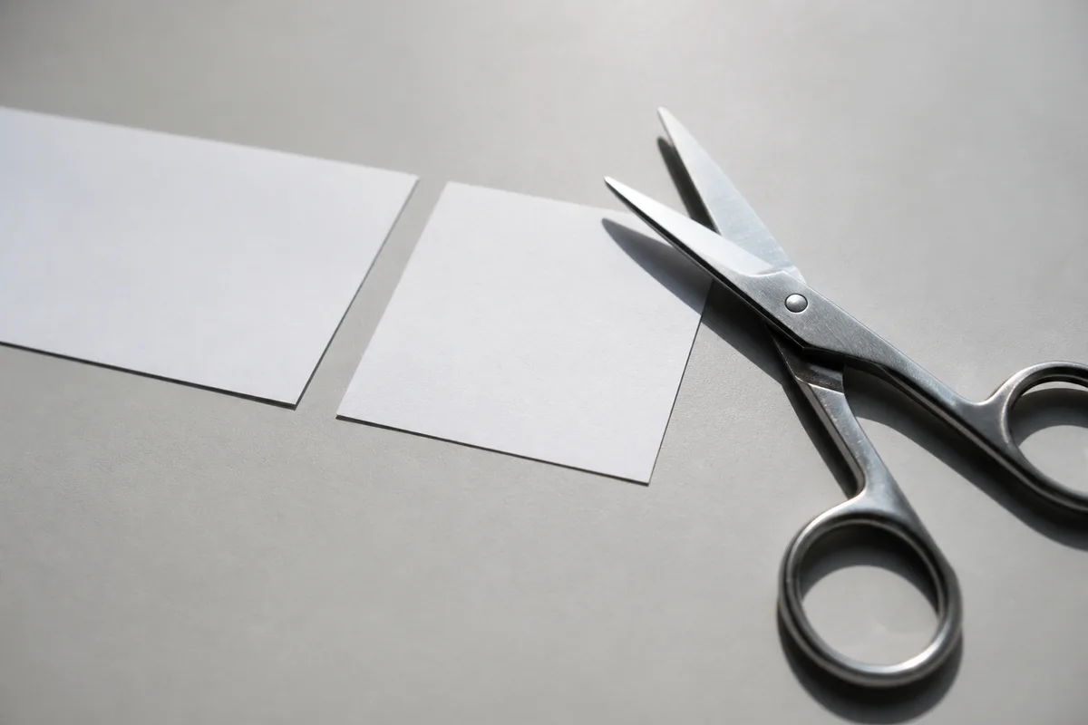 Ciseaux de bureau à côté d&rsquo;une bande de papier uni coupée en deux parties inégales
